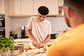 Young man cutting onion in kitchen