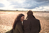Couple in coats on sunny windy winter beach