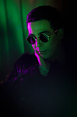 Young man wearing sunglasses in dark