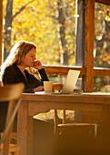 Businesswoman working on laptop in sunny cafe