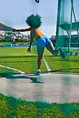 Female track and field athlete throwing discus