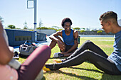 Male runners resting and talking on sunny field