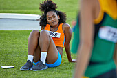 Female track and field athlete resting on grass