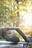 Woman riding in convertible in sunny autumn park