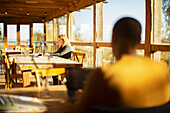 Business people working on laptops in sunny cafe