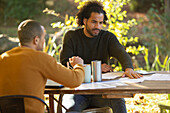 Businessmen discussing paperwork at table in park