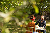 Couple enjoying cake at table in sunny summer orchard