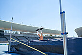 Female track and field athlete falling over high jump