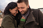 Happy affectionate couple in winter coats hugging