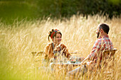 Happy couple relaxing at table in sunny tall grass