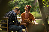 Happy couple with golden retriever dog at garden table