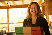 Happy female pizzeria owner with pizza boxes