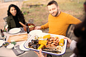 Woman serving fresh seafood to friends at patio table