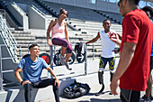 Young athletes talking in sunny sports stadium