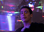 Young man under neon lights in night club