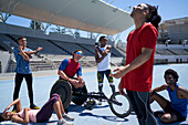 Happy athletes stretching on sunny sports track