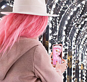 Woman with pink hair taking selfie under lights