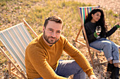 Confident man relaxing in lawn chair by girlfriend