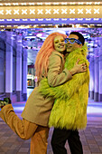 Happy couple hugging under neon lights on sidewalk
