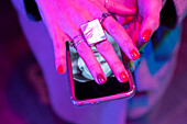 Hand of woman with red manicure covering smart phone