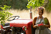 Happy proud woman at tractor with fresh red currants