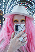 Woman with pink hair and fedora taking selfie
