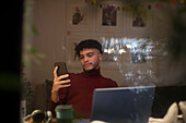 Young man working from home with smart phone and laptop