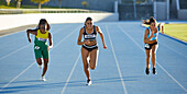 Female track and field athletes competing on sunny track