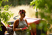 Happy woman with fresh harvested red currants at tractor