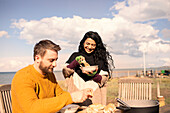 Couple enjoying chowder and baguette on sunny beach patio