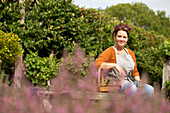 Happy woman taking a break from gardening in sunny garden