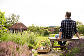 Man taking a break from gardening in sunny cottage garden