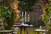 Champagne and red currants on table with candles in garden