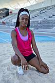 Confident female track and field athlete in long jump sand