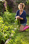 Proud woman harvesting fresh vegetables in garden