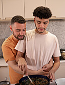 Affectionate gay male couple cooking and hugging in kitchen