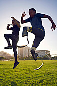 Coach and young male amputee athlete training in sunny park