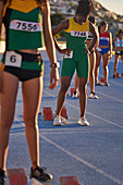 Female track and field athletes preparing at starting blocks
