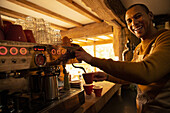 Happy male barista preparing coffee at cafe espresso machine