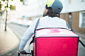 Bike messenger in helmet delivering food on urban street