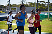 Smiling athletes running on sports track