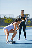Female athlete stretching with trainer on track