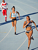 Female athletes running on track in competition