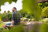 Happy man taking break from gardening on bench in garden