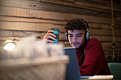 Young man with coffee and headphones working from home