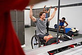 Confident wheelchair athlete cheering in locker room mirror
