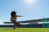 Female athlete throwing shot put in stadium