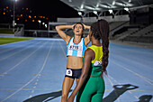 Female athletes resting on stadium track at night