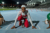 Determined runner in hijab at track starting line