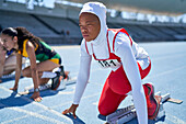 Female athlete in hijab at starting block on track